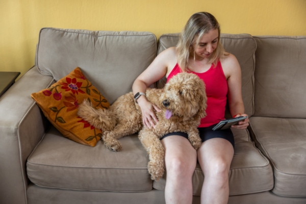 A lady sitting and playing with a goldendoodle on a Sofa in Miami, FL